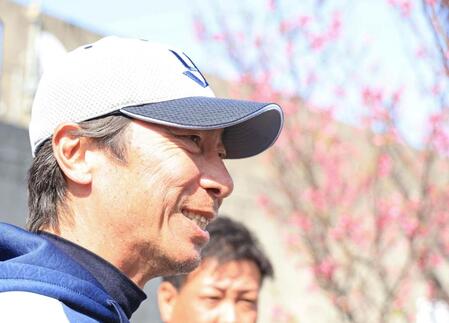 　寒緋桜の前で笑顔を見せる高津監督（撮影・吉澤敬太）