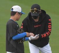 　奈良間（左）の左手を見る新庄監督（撮影・佐藤厚）