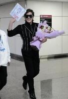 　台北に到着し、空港でファンから色紙をもらって笑顔でポーズをとる新庄監督