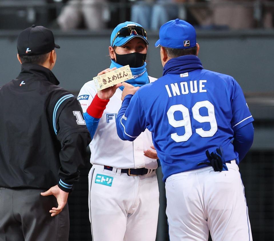 　メンバー表交換の際に井上監督（右）から「きよめぱん」を受け取る新庄監督（中央）＝撮影・中島達哉