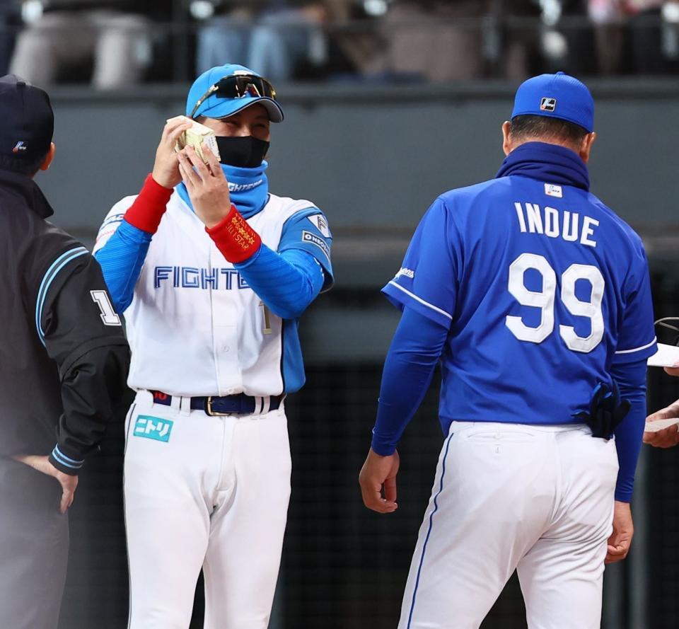 　メンバー表交換の際に井上監督（右）から「きよめぱん」を受け取り、笑みがこぼれる新庄監督（中央）＝撮影・中島達哉