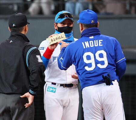 　メンバー表交換の際に井上監督（右）から「きよめぱん」を受け取る新庄監督（中央）＝撮影・中島達哉