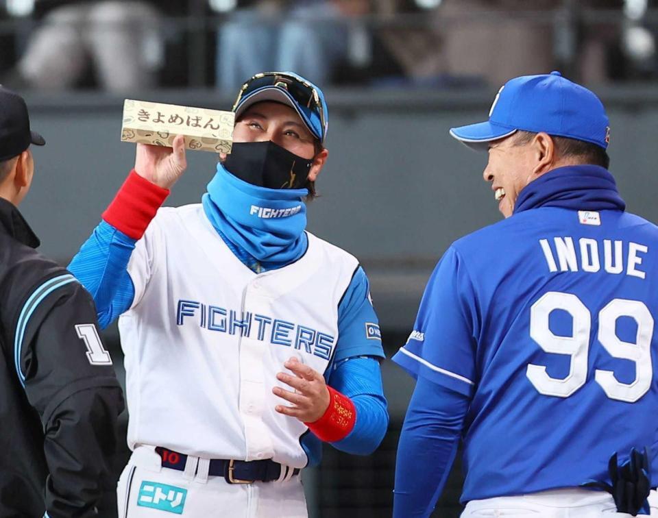 　井上監督（右）から「きよめぱん」をもらい、笑顔を見せる新庄監督