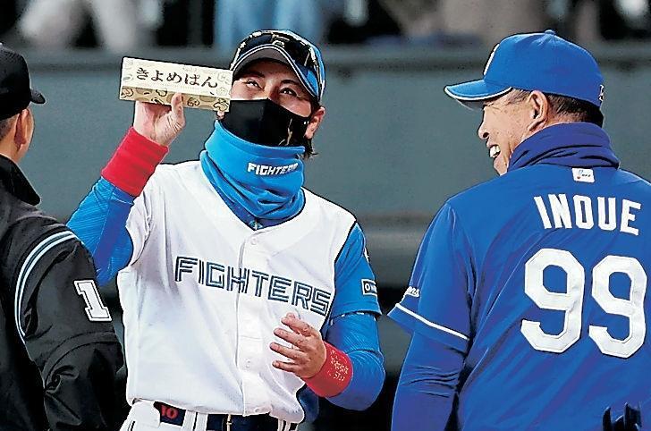 　メンバー表を交換し、井上監督（右）から「きよめぱん」をもらい、笑顔を見せる新庄監督（９日）