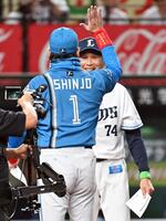 　試合前のメンバー表交換で新庄監督（手前）とハイタッチをする西口監督