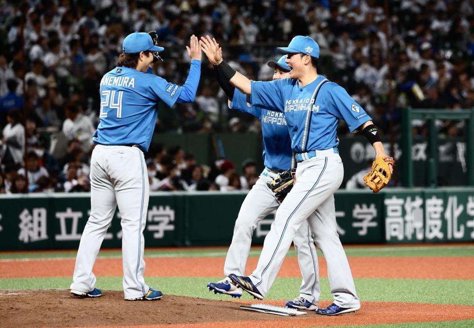 　開幕戦で完封勝利をあげた金村（左）とタッチを交わす清宮幸