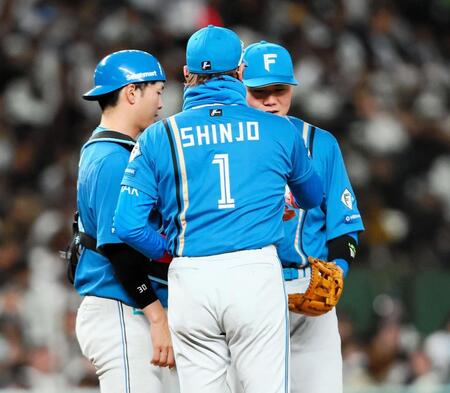 　８回、マウンドに向かった新庄監督（１）からカイロを手渡される清宮幸（右）＝撮影・中島達哉