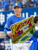 　通算千投球回を達成し、記念ボードを手にする松葉