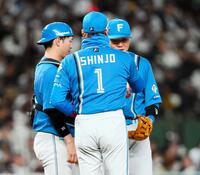 　８回、マウンドに向かった新庄監督（１）からカイロを手渡される清宮幸（右）＝撮影・中島達哉