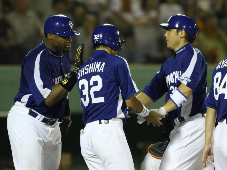 　現役時代に本塁打を放ってブランコ氏（左）から迎えられる森野打撃・作戦コーチ（右）＝２０１０年７月