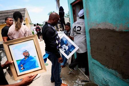 　亡くなったトニ・ブランコさんの写真を持つ人々（ロイター＝共同）