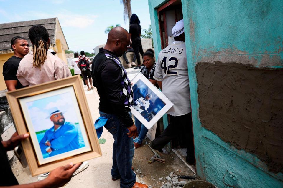 　亡くなったトニ・ブランコさんの写真を持つ人々（ロイター＝共同）