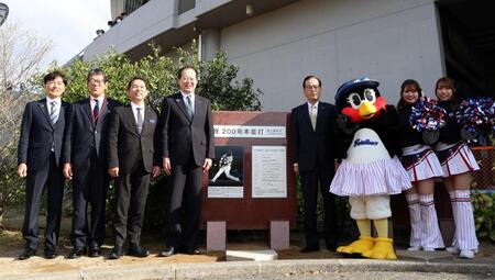 　　記念石碑と写真に納まるヤクルト代表取締役社長オーナー代行・林田哲哉氏（右から４人目）とヤクルト松山協力会会長であり、松山市長の野志克仁氏（同５人目）ら（撮影・北村雅宏）