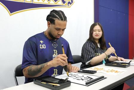 　オリ姫の松尾未知留（右）さんと書道に挑戦するエスピノーザ（撮影・坂部計介）