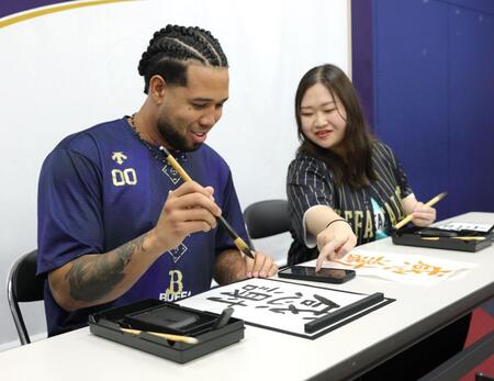　オリ姫の松尾未知留（右）さんと書道に挑戦するエスピノーザ（撮影・坂部計介）