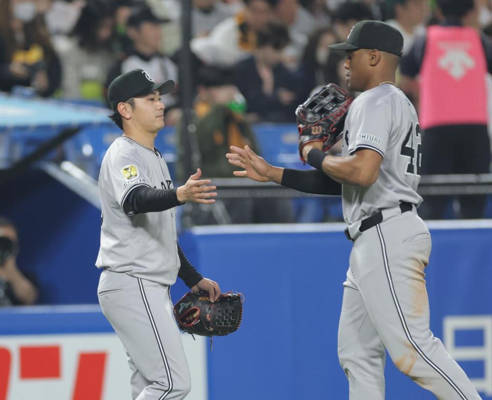 　３回を無失点で終え、ヘルナンデス（右）とタッチを交わす石川（撮影・西岡正）