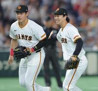 　開幕から２９イニング無失点の球団記録を更新し、岡本（左）と喜び合う山崎（撮影・西岡正）