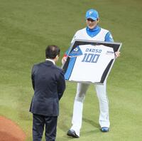 　球団初代オーナー大社義規氏が背負った永久欠番の１００番の背番号が入ったユニホームを贈呈する新庄監督（右）＝撮影・中島達哉