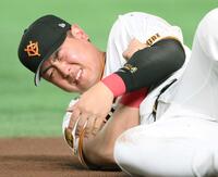 　腕を押さえ顔をゆがめる岡本