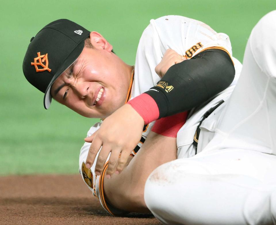 　腕を押さえ顔をゆがめる岡本