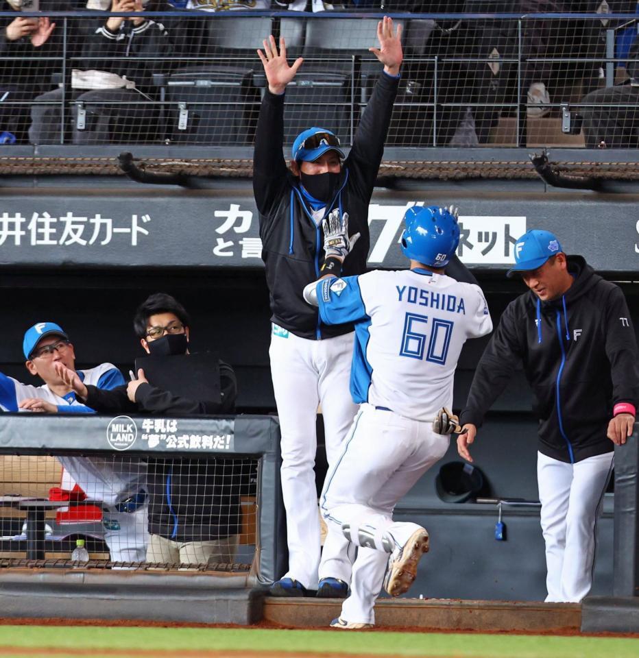 　１回、先頭打者本塁打を放った吉田（６０）をハイタッチで迎える新庄監督（中央）＝撮影・中島達哉