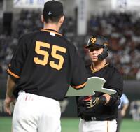 　通算１５００安打を達成した中田にボードを渡す秋広＝２３年６月