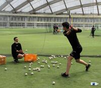 　阿部ヘッドコーチ（左）がトスを上げる中でティー打撃を行う秋広＝２２年１１月