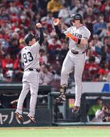 　８回、同点２ランを放ち、ジャンプして松本コーチ（左）とタッチをするキャベッジ＝撮影・市尻達拡