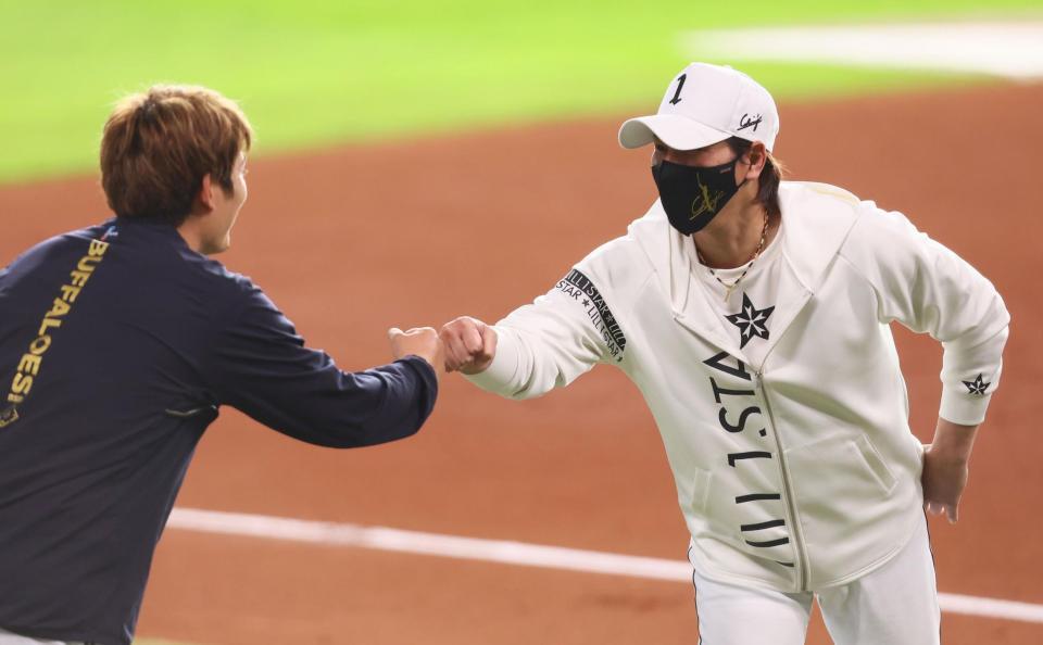 　試合前、オリックス・九里（左）とグータッチを交わす新庄監督（撮影・中島達哉）