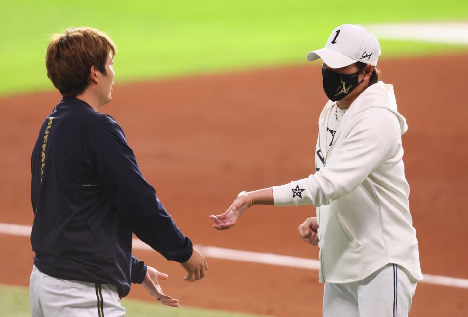 　試合前、オリックス・九里（左）とスクイズのシーンの話をする新庄監督（撮影・中島達哉）