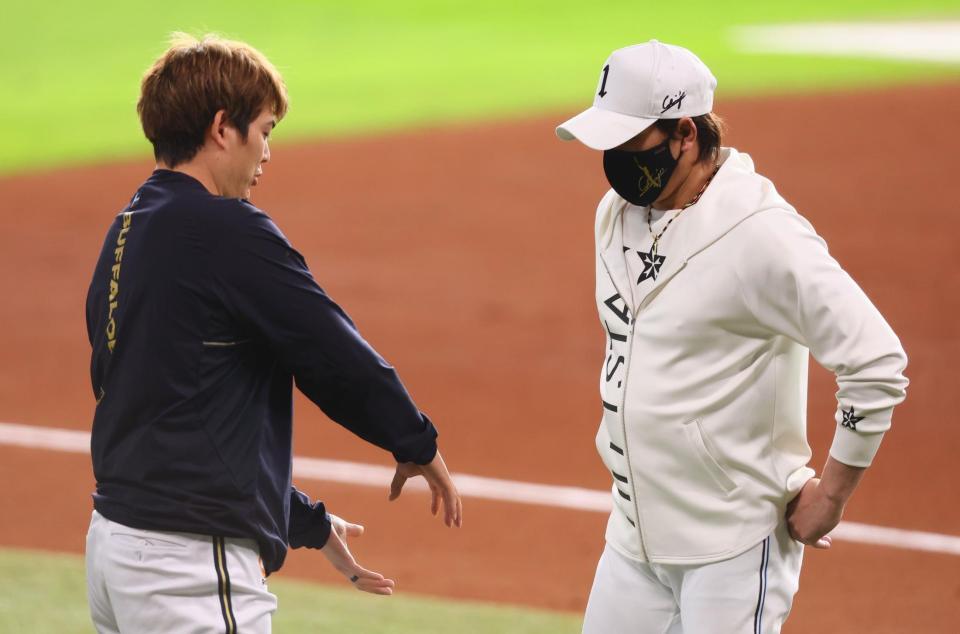 　試合前、オリックス・九里（左）とスクイズのシーンの話をする新庄監督（撮影・中島達哉）