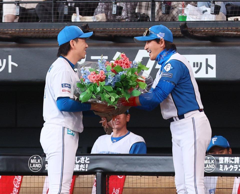 　８８０試合連続救援登板の日本記録を達成した宮西（左）に花束を手渡す新庄監督（撮影・中島達哉）