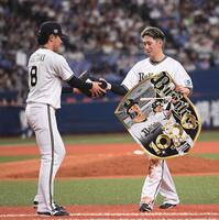 　通算１０００試合出場を達成し、麦谷（左）から記念ボードを受け取る西川（撮影・西田忠信）