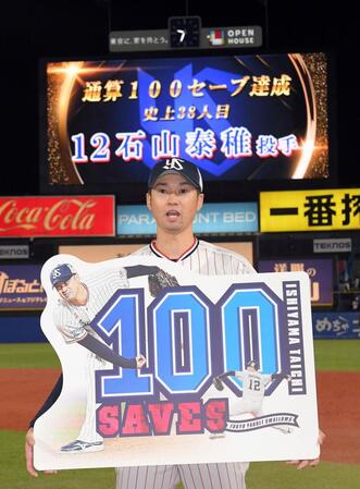 　通算１００セーブを達成し、ボードを持つ石山（撮影・佐藤厚）