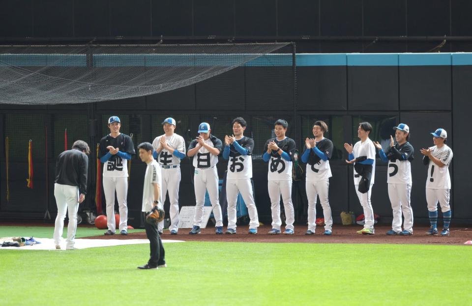 　試合前練習中、サプライズで投手陣から２日の誕生日を祝福される宮西（左）＝撮影・西岡正