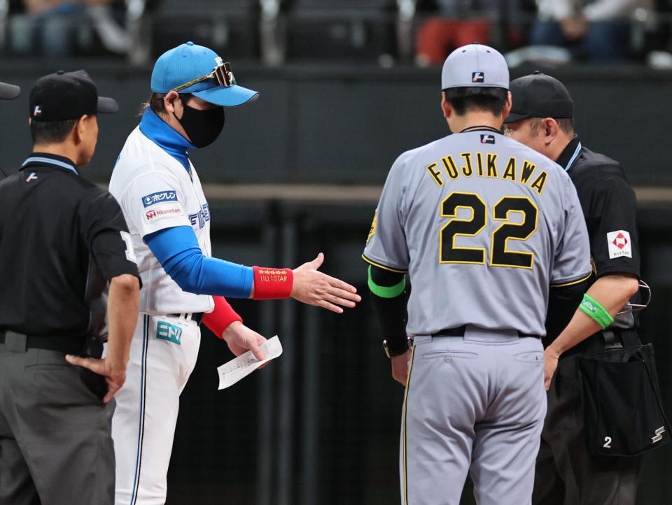 　お互い握手せずメンバー表の確認をする新庄監督と藤川監督（撮影・田中太一）