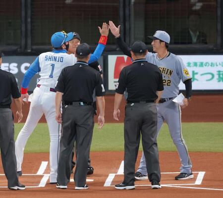 　メンバー表交換で新庄監督（左）、審判団と手を合わせた後、ハイタッチする藤川監督（撮影・西岡正）