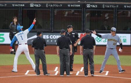 　メンバー表交換で新庄監督（左）、審判団と手を合わせた後、打ち合う藤川監督（撮影・西岡正）