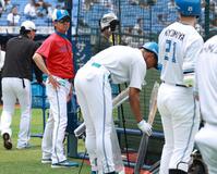 　還暦祝いの赤いユニホームで練習を見る八木打撃コーチ（撮影・金田祐二）