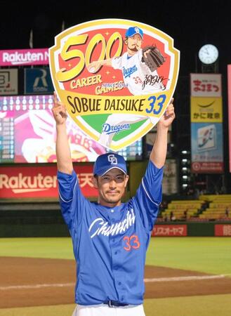 　通算５００試合登板を達成し記念ボードを掲げる祖父江