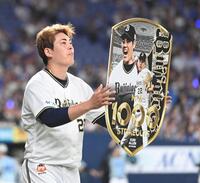 通算１０００奪三振を達成し、記念ボードを掲げる九里（撮影・飯室逸平）