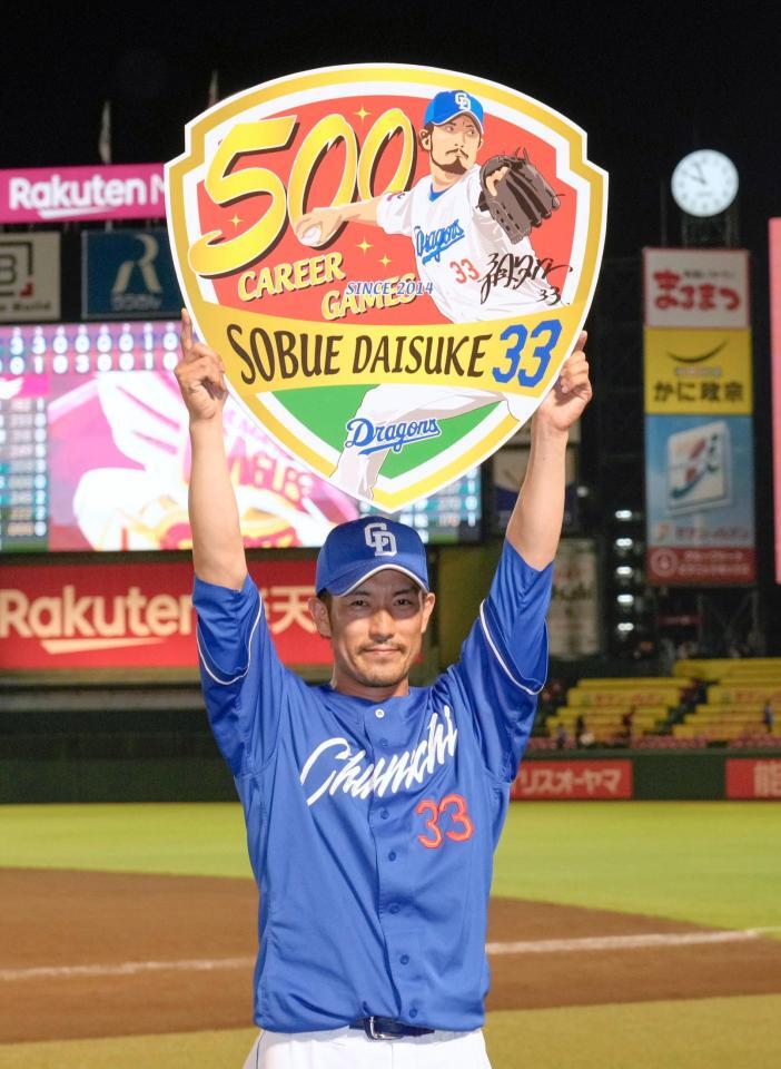 　通算５００試合登板を達成し記念ボードを掲げる祖父江