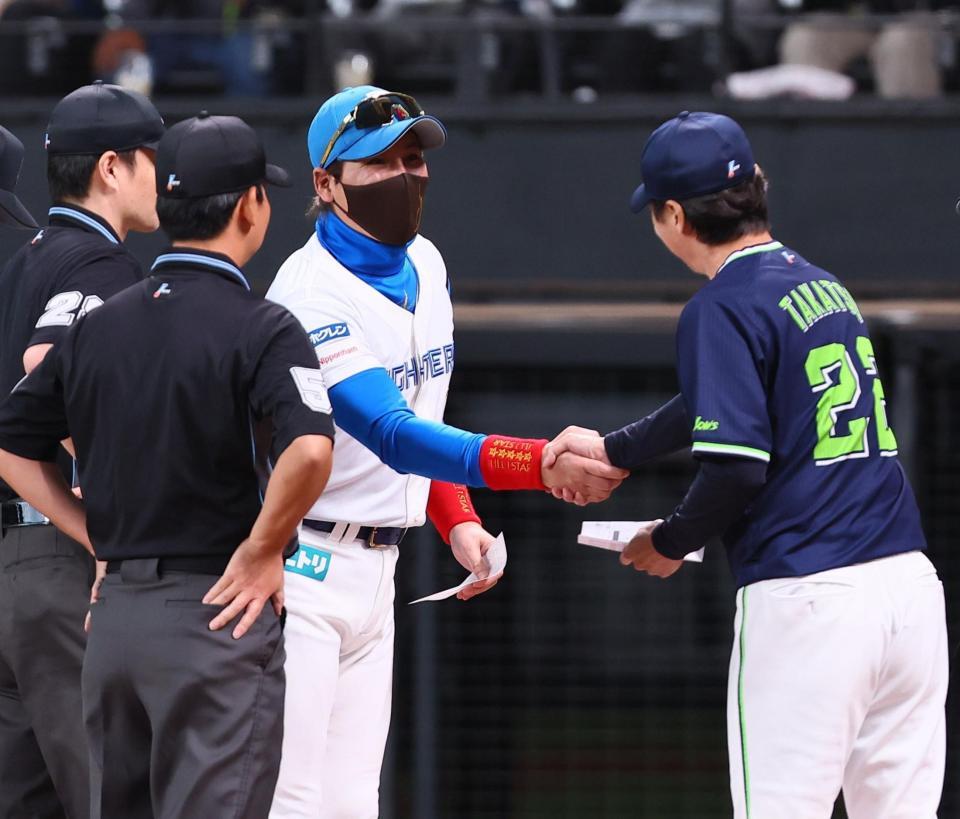 　メンバー表を交換し、高津監督（右）と握手を交わす新庄監督（中央）＝撮影・中島達哉