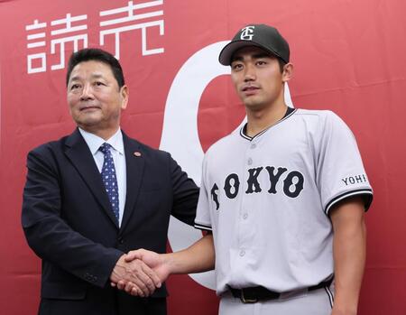 　支配下登録され吉村禎章編成本部長（左）と握手を交わす三塚（撮影・立川洋一郎）