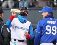 　メンバー表を交換し、井上監督（右）から「きよめぱん」をもらい、笑顔を見せる新庄監督（中央）＝３月９日