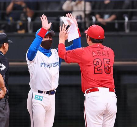 　メンバー表を交換し、新井監督（右）と両手でハイタッチを交わす新庄監督（撮影・中島達哉）