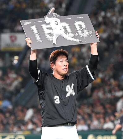 　１５００試合出場の記念ボードを掲げる角中（撮影・飯室逸平）