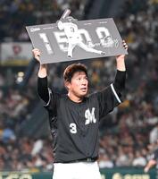 　１５００試合出場の記念ボードを掲げる角中（撮影・飯室逸平）