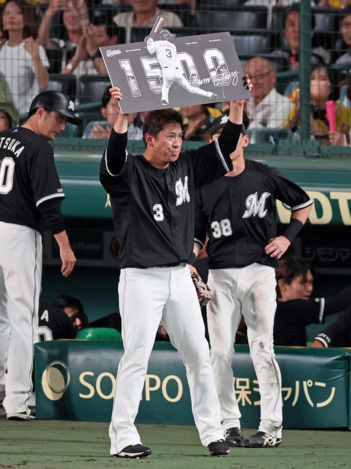 　１５００試合出場を達成し記念ボードを掲げる角中（撮影・立川洋一郎）