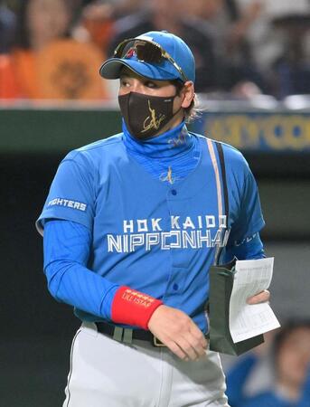 　深緑の紙袋を手に試合前のメンバー表交換に向かう新庄監督（撮影・伊藤笙子）